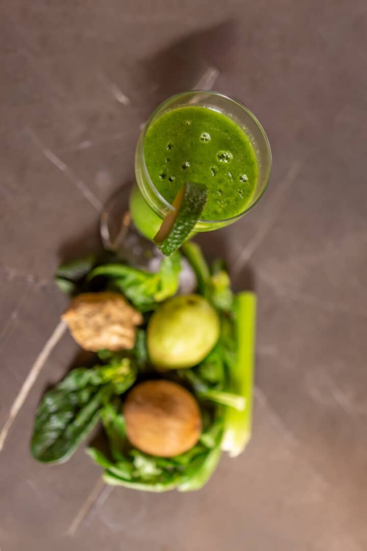 Aerial view of a fresh Green smoothie served in a tall glass with spinach avocado and kiwi.