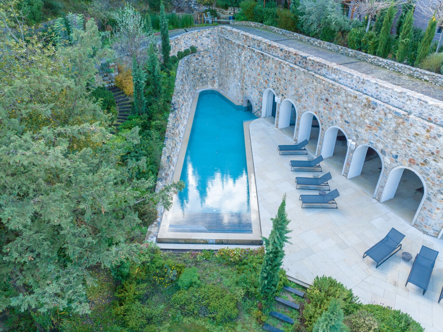 Aerial view of the rectangular pool with sun loungers at Euphoria Retreat nestled at the edge of the forest.