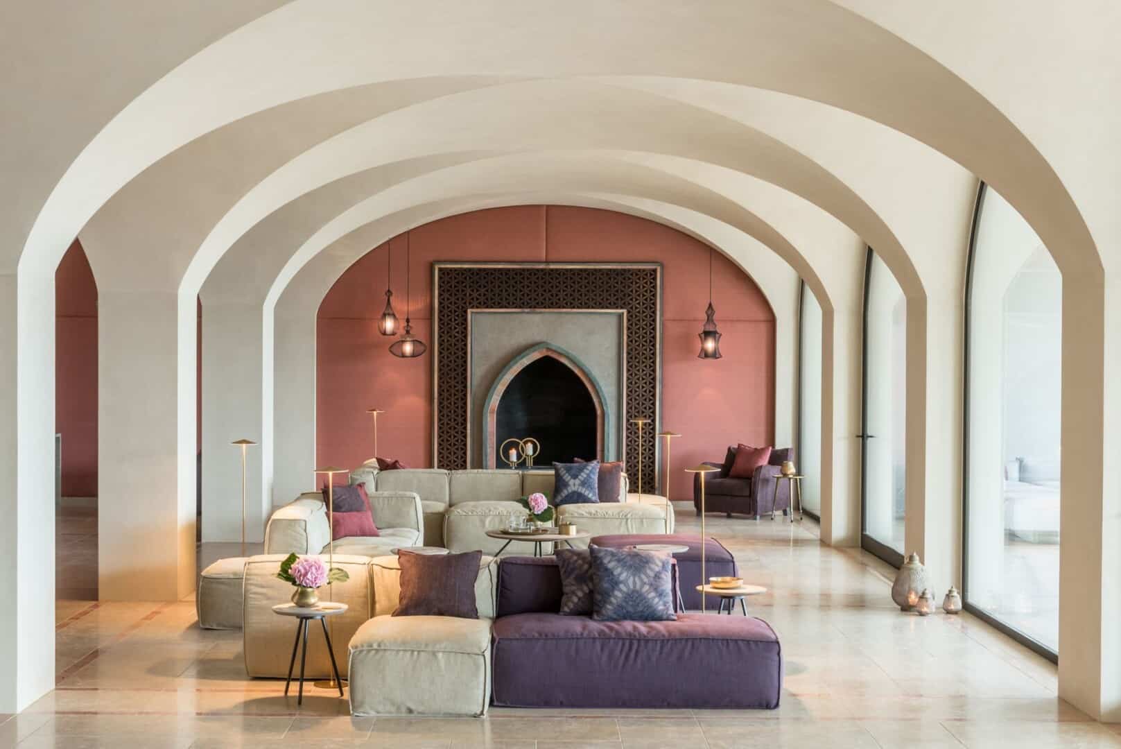 Clean arches at Euphoria Retreat with boho-chic living room in shades of beige and purple, featuring a Moroccan wall piece.